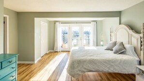 Un dormitorio con una cama grande, un aparador y una puerta que da a un balcón.