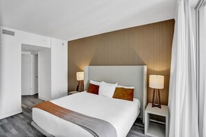 Ein modernes Hotelzimmer mit einem großen Bett, zwei Nachttischen und einer neutralen Farbgestaltung.