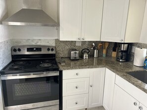 A kitchen with white cabinets, a stainless steel stove, a toaster, and a coffee maker.
