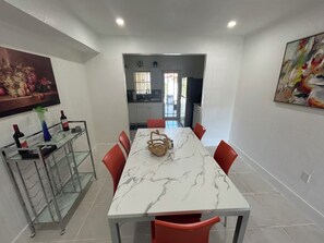 A dining area with a marble table, red chairs, and a glass cabinet with wine bottles.