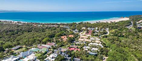 Vista aérea de uma área residencial costeira com casas, uma praia e um céu azul e límpido.