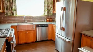 Una cocina con armarios de madera, un refrigerador de acero inoxidable, un lavavajillas y una estufa a gas.