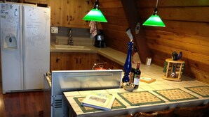 A kitchen with wooden cabinets, a refrigerator, a sink, and a dining table with chairs. - Govy A Frame w/ Hot Tub. (Government Camp)