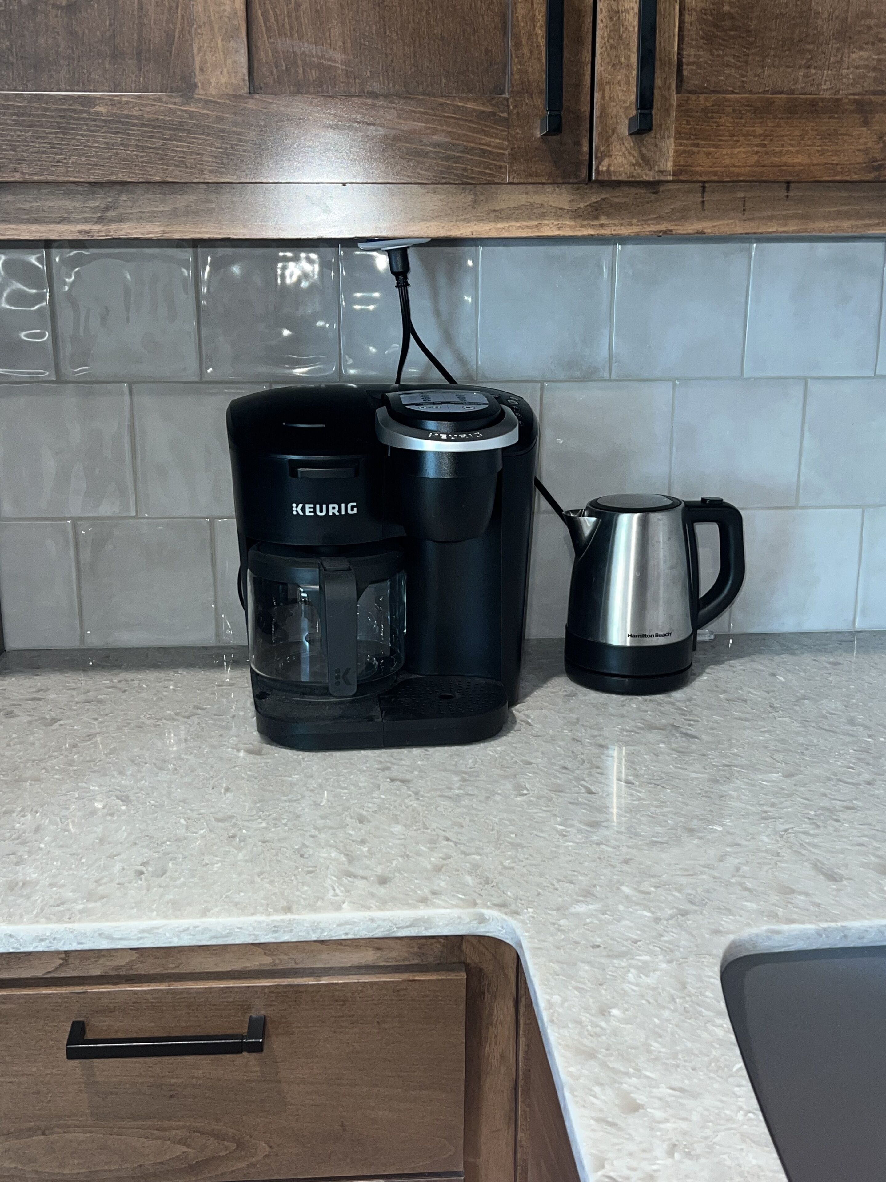 Una cocina con una cafetera Keurig, una cafetera Hamilton Beach y un armario de madera.