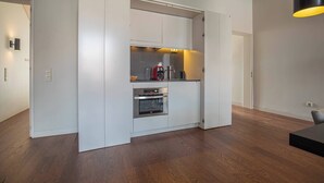 A modern kitchen with white cabinetry, a built-in oven, and a coffee machine. - 8 Building Apartment 403 [T2] - River & Garden View (Lisboa)