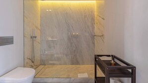 A modern bathroom with a marble shower enclosure, a white toilet, and a wooden vanity with a towel. - 8 Building Apartment 403 [T2] - River & Garden View (Lisboa)