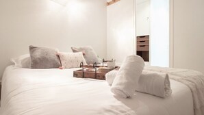 A neatly made bed with white linens, a tray with toiletries, and a towel on the side. - L Ourson vue Lac (Annecy)