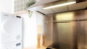 A kitchen with a stainless steel range hood, a Bosch washing machine, and a glass container of spaghetti. - L Ourson vue Lac (Annecy)