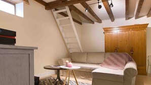 A cozy room with a loft bed, a wooden wardrobe, a sofa, and a small table with candles. - Cocoon 1 min romantique (Annecy)
