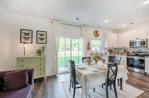 A modern kitchen with white cabinets, stainless steel appliances, and a dining area with a table set for four. - Charlie's House -8 min.to Historic Summerville/30 min to Charleston and Airport (Summerville)