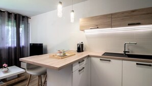 Een moderne keuken met een houten aanrecht, witte kasten, een zwarte spoelbak en hangende lampen.