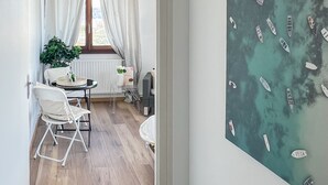 A room with a wooden floor, a dining table with chairs, a potted plant, and a window with curtains. - Mount Royal balcony with mountain view (Annecy)