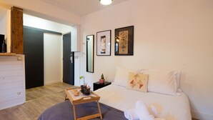 A hotel room with a bed, a bedside table with a tray of breakfast, a small potted plant, and framed artwork on the wall. - Petit chez-vous pré carré rue Vaugelas (Annecy)