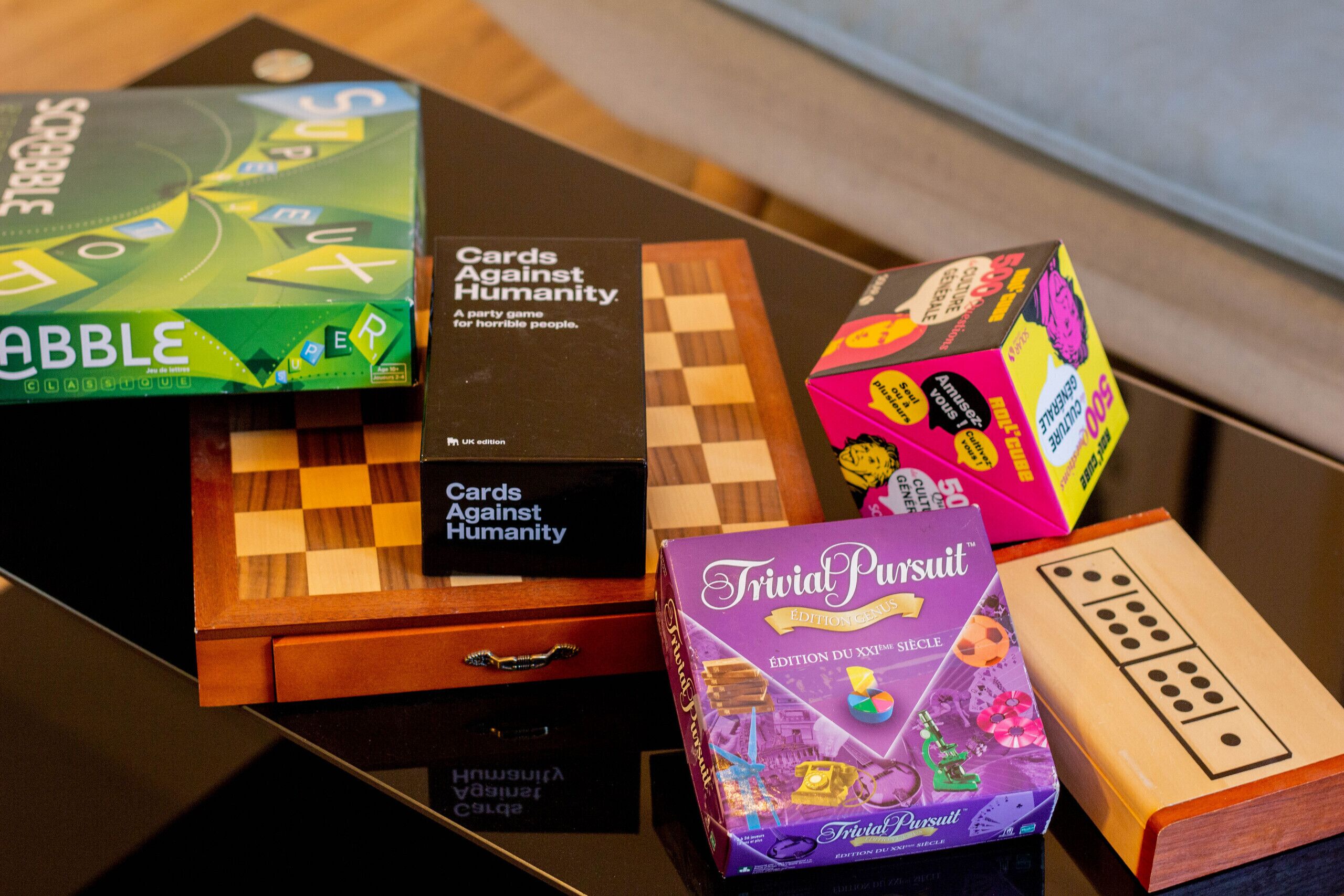 Verschiedene Brettspiele, darunter 'Cards Against Humanity' und 'Trivial Pursuit', stehen auf einem Tisch.