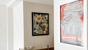 A room with a wooden table, a sink, and a framed abstract painting on the wall. - Central Park au centre ville, appareil raclette (Annecy)