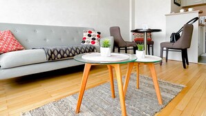 A modern living room with a grey sofa, two armchairs, a glass coffee table, and a small side table. - Central Park au centre ville, appareil raclette (Annecy)