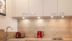A modern kitchen with a sink, a red toaster, a red coffee maker, and a countertop. - Central Park au centre ville, appareil raclette (Annecy)