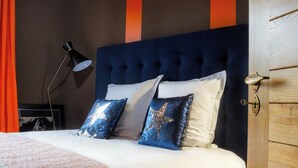 Un lit bien fait, avec une tête de lit capitonnée, deux oreillers et une lampe de chevet.