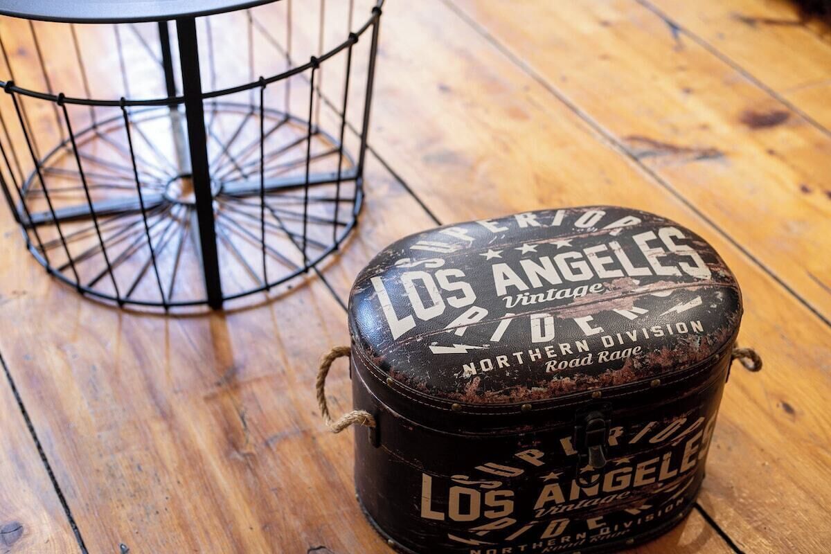 A vintage-style metal container with "Los Angeles" and "Northern Division" text, placed on a wooden floor.