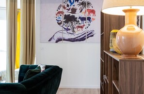 Uma sala de estar com um sofá verde escuro, um aparador de madeira e uma luminária fixada na parede.
