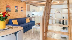 Et moderne køkken med træbjælker, en blå sofa og et spiseområde med bord og stole.