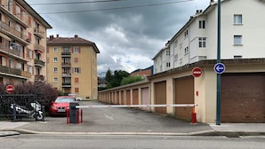 Un lotissement résidentiel fermé, avec des immeubles d’appartements, une voiture rouge garée et un panneau indiquant l’interdiction d’accès.
