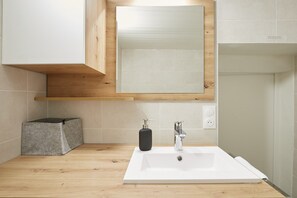 A bathroom with a white sink, a mirror, a soap dispenser, and a towel. - Moka rue Carnot, emplacement 1er (Annecy)