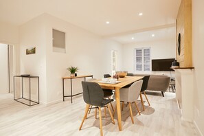 A modern dining area with a wooden table, four chairs, a small side table, and a potted plant. - Moka rue Carnot, emplacement 1er (Annecy)