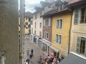 A narrow street with buildings on either side, a sign for 'minelli' store, and a '50%' sale sign. - Moka rue Carnot, emplacement 1er (Annecy)