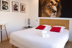 Ein Hotelzimmer mit einem großen Bett, zwei roten Kissen, einem hölzernen Kopfteil und einer Wand mit drei gerahmten Fotografien.