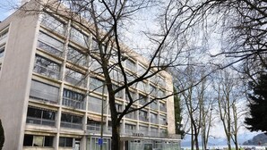 Ein mehrstöckiges Gebäude mit Balkonen, einem Parkplatz und Blick auf ein Gewässer.