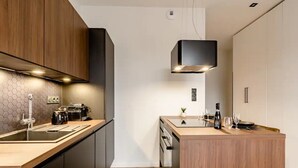 A modern kitchen with wooden cabinets, a central island, and a built-in oven. - Jacuzzi Bay (Annecy)