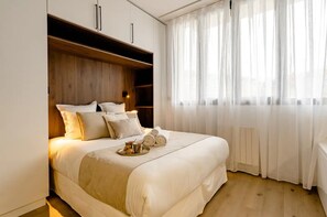 A neatly made bed with pillows, a tray with towels, and a bedside table with a lamp. - Jacuzzi Bay (Annecy)