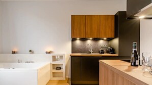A modern kitchen with a central island, built-in appliances, and a wooden cabinet above the countertop. - Jacuzzi Bay (Annecy)