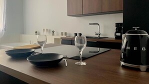 A modern kitchen with a wooden countertop, two wine glasses, a black pan, and a black coffee maker. - Jacuzzi Bay (Annecy)