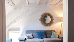 Un salon moderne avec un canapé gris, un miroir en forme de soleil et une petite table blanche.