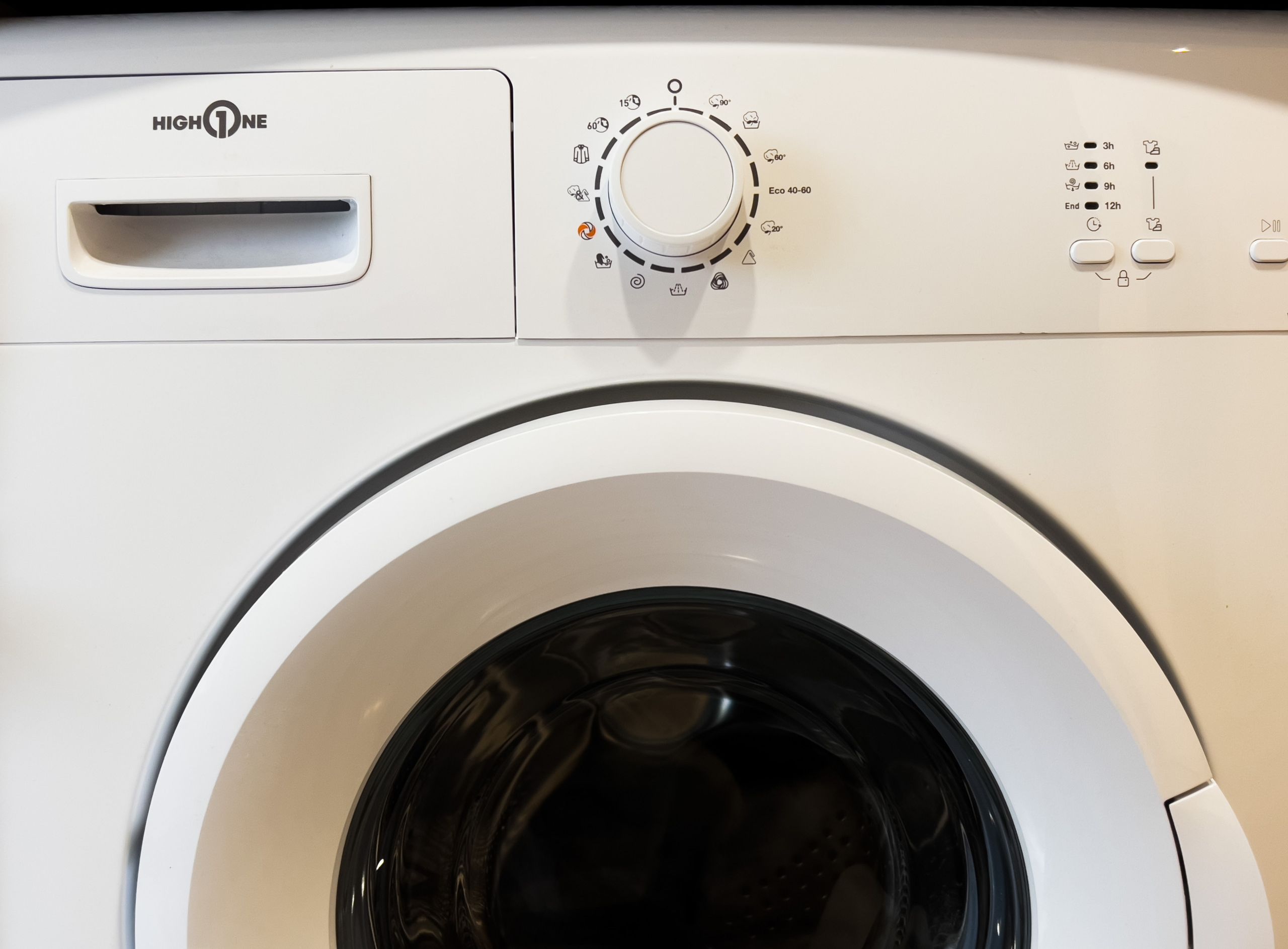 A front view of a white washing machine with a control panel featuring a dial, buttons, and a brand name.