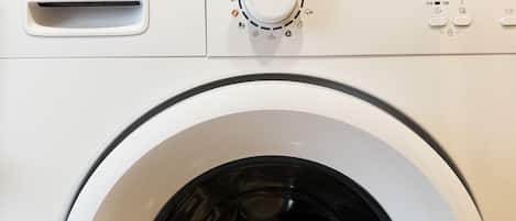 A front view of a white washing machine with a control panel featuring a dial, buttons, and a brand name.