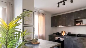 A modern kitchen with dark cabinets, a built-in oven, and a dining area with a table and bench.