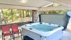 Un jacuzzi con un escalón, dos sillas rojas y un muro de piedra de fondo.