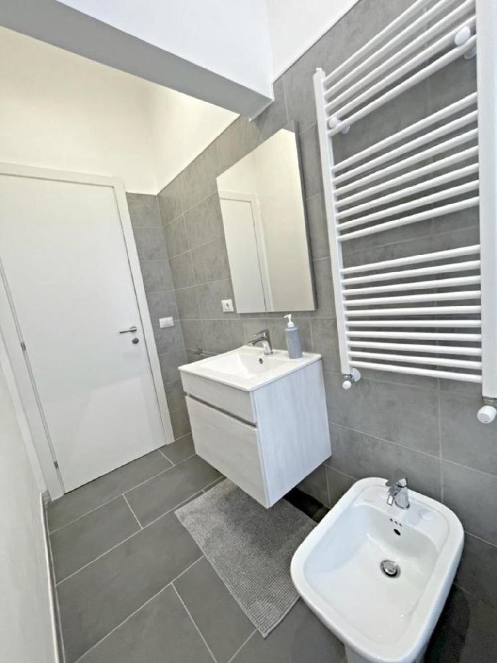 Une salle de bain moderne avec un lavabo blanc, un miroir et un porte-serviettes.