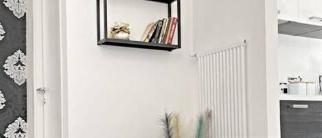 Una sala de estar moderna con dos sillones negros, una mesita redonda con tazas y platillos, y una estantería arriba.