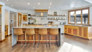 Una cocina moderna con una isla grande, armarios de madera y vistas al exterior.
