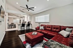 A modern living room with a red leather sofa, a coffee table, and a ceiling fan.