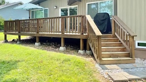 A residential deck with a wooden railing, a covered grill, and a set of stairs leading to the house. - Lake View! Hot-Tub! Beaver Lake House! (Rogers)
