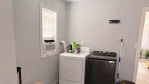 A compact laundry room with a washing machine, dryer, and a small table.