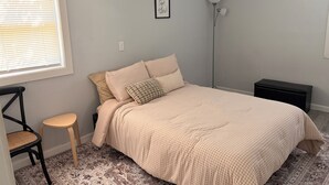 A bedroom with a bed, a chair, a floor lamp, and a small bedside table.