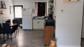 A compact kitchen with a refrigerator, microwave, and sink. There is a dining area with a table and chairs.