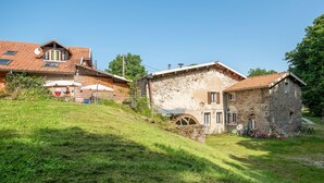 A traditional stone building with a sloped roof, a small water wheel, and a grassy hill in the foreground. - Pet friendly home in Escles with WiFi (Escles)