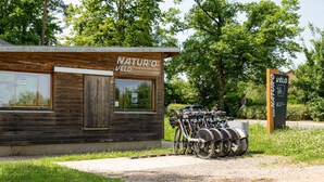 A wooden building labeled "NATURO VÉLO" with a sign indicating a parking area for bicycles. - Pet friendly home in Escles with WiFi (Escles)